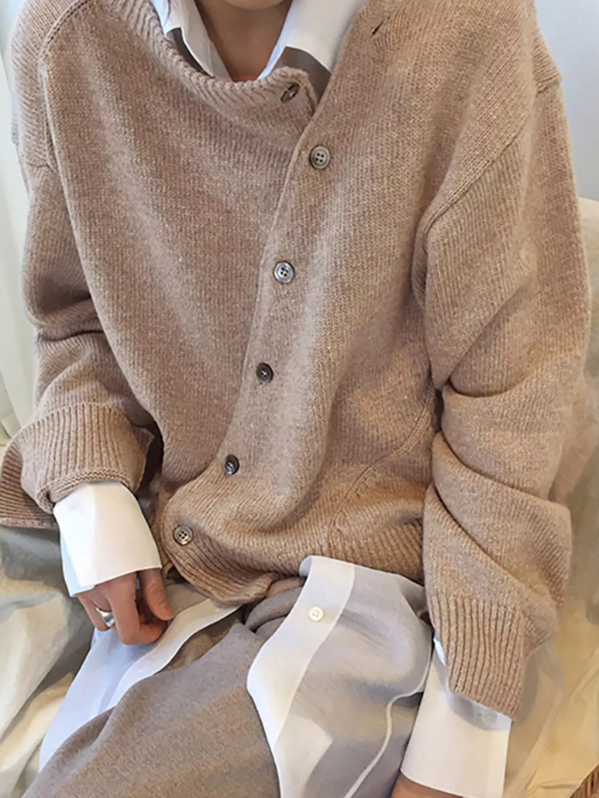 Asymmetric button-down sweater by Trendsi featuring a stylish, modern design with unique button placement and soft knit fabric.