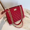 Red women's tote handbag with embossed design and gold chain straps.