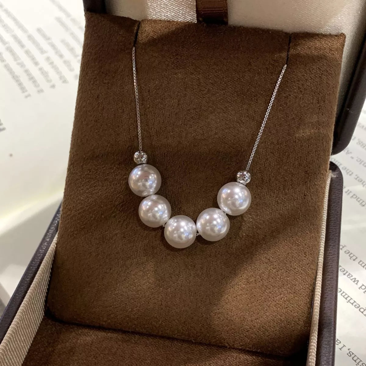 Adjustable pearl necklace from Plush Fashion Hub featuring a string of elegant white pearls on a delicate chain.