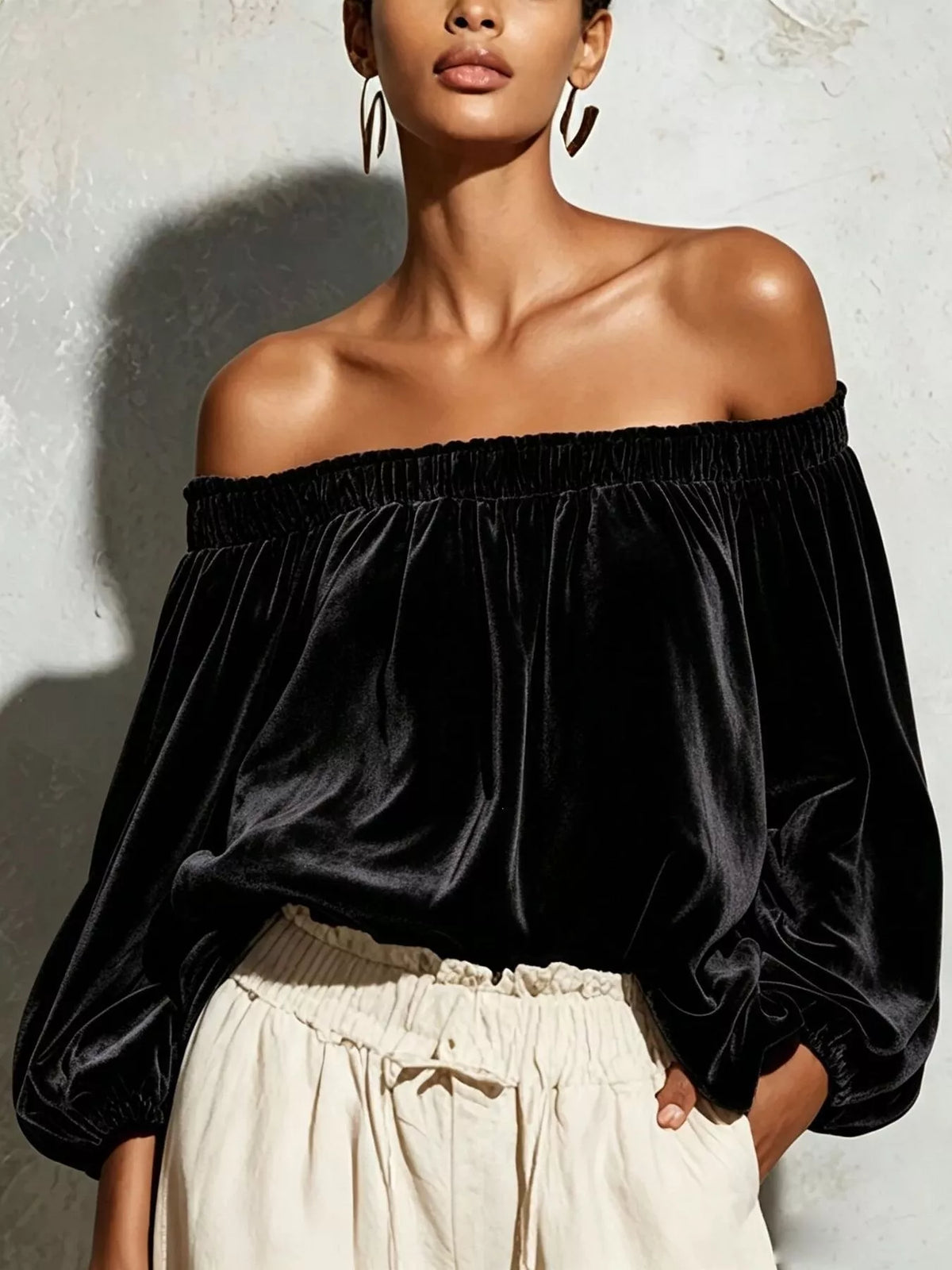 Black off-shoulder velvet long sleeve T-shirt from Trendsi, featuring a fitted design and soft fabric for stylish comfort.