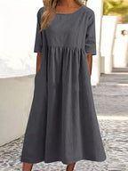 Plus size midi casual dress by FitiqueFit with a round neckline and front pockets, shown on a model.