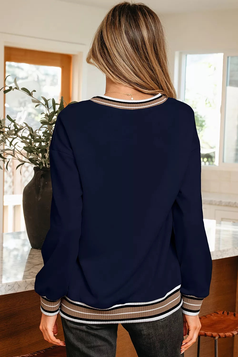 Contrast striped trim V-neck sweatshirt by Trendsi featuring a relaxed fit and stylish design, shown on a model.
