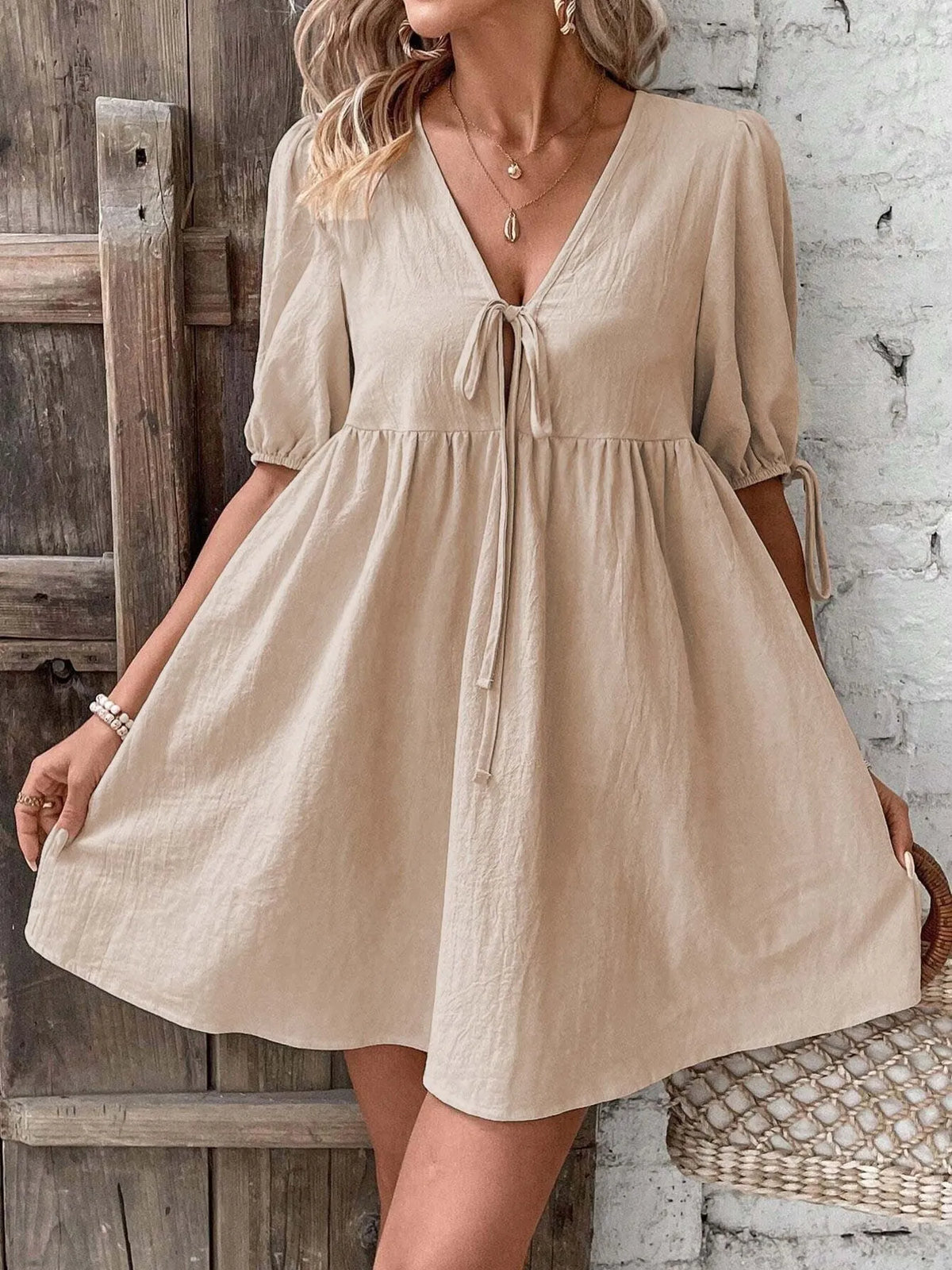 Cotton V-neck tie-front mini dress with puff sleeves by Plush Fashion Hub, showing the front view with a fitted waist and playful style.