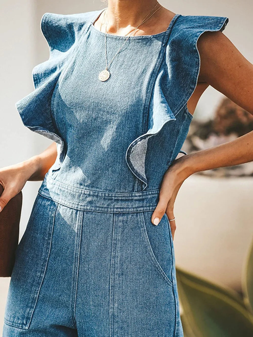 Backless sleeveless denim jumpsuit with ruffled details, featuring a trendy fit and casual style, from Trendsi.