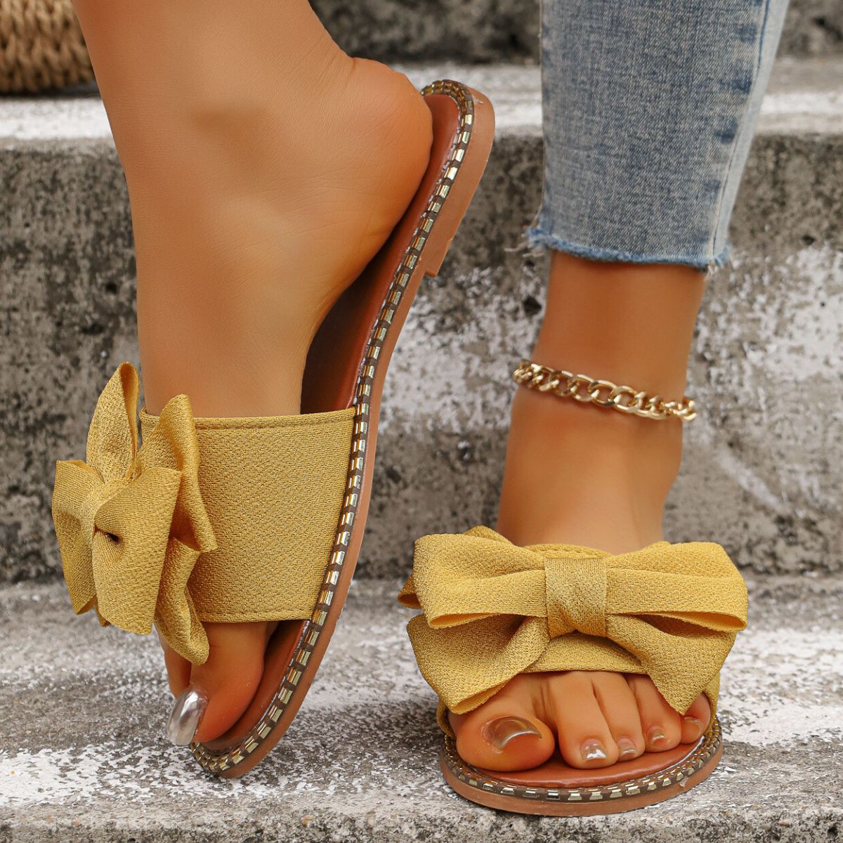 Plush Fashion Hub bowknot embellished flat sandals with open toes and ankle straps on a neutral background.