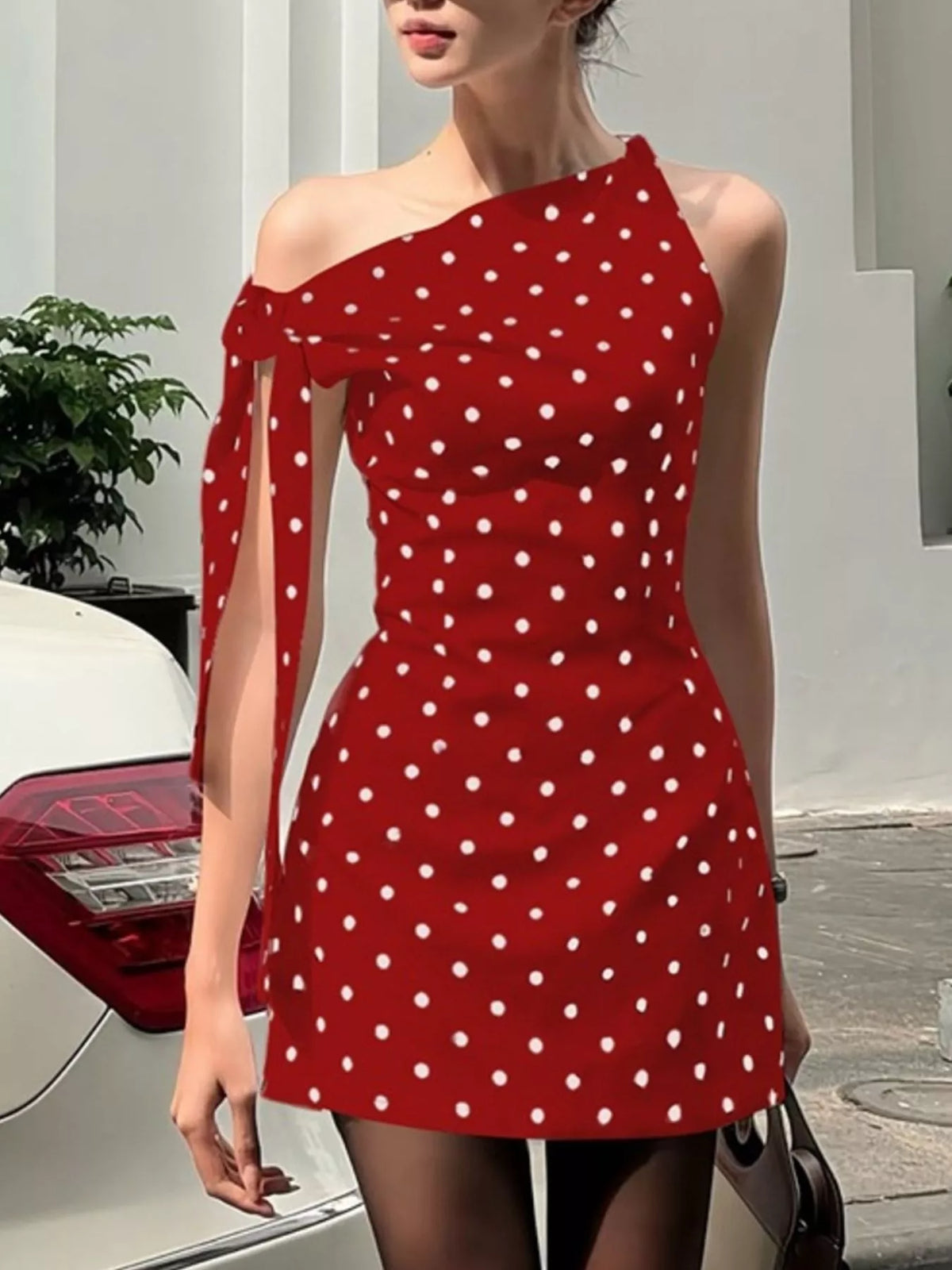 Polka dot sleeveless mini dress with bow accents by Plush Fashion Hub, showcasing a stylish dress with a fitted waist and playful pattern.