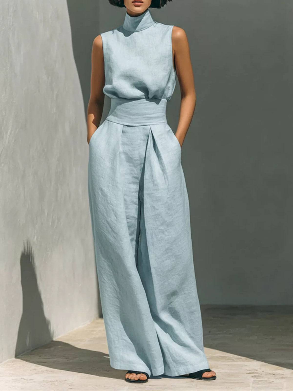 Plus size full length sleeveless jumpsuit with wide-leg design and smocked waist, featuring a trendy, comfortable fit.