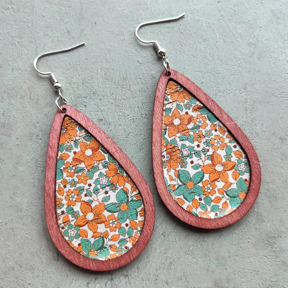 Floral wood teardrop earrings with colorful flower patterns, crafted by Plush Fashion Hub, hanging on display.