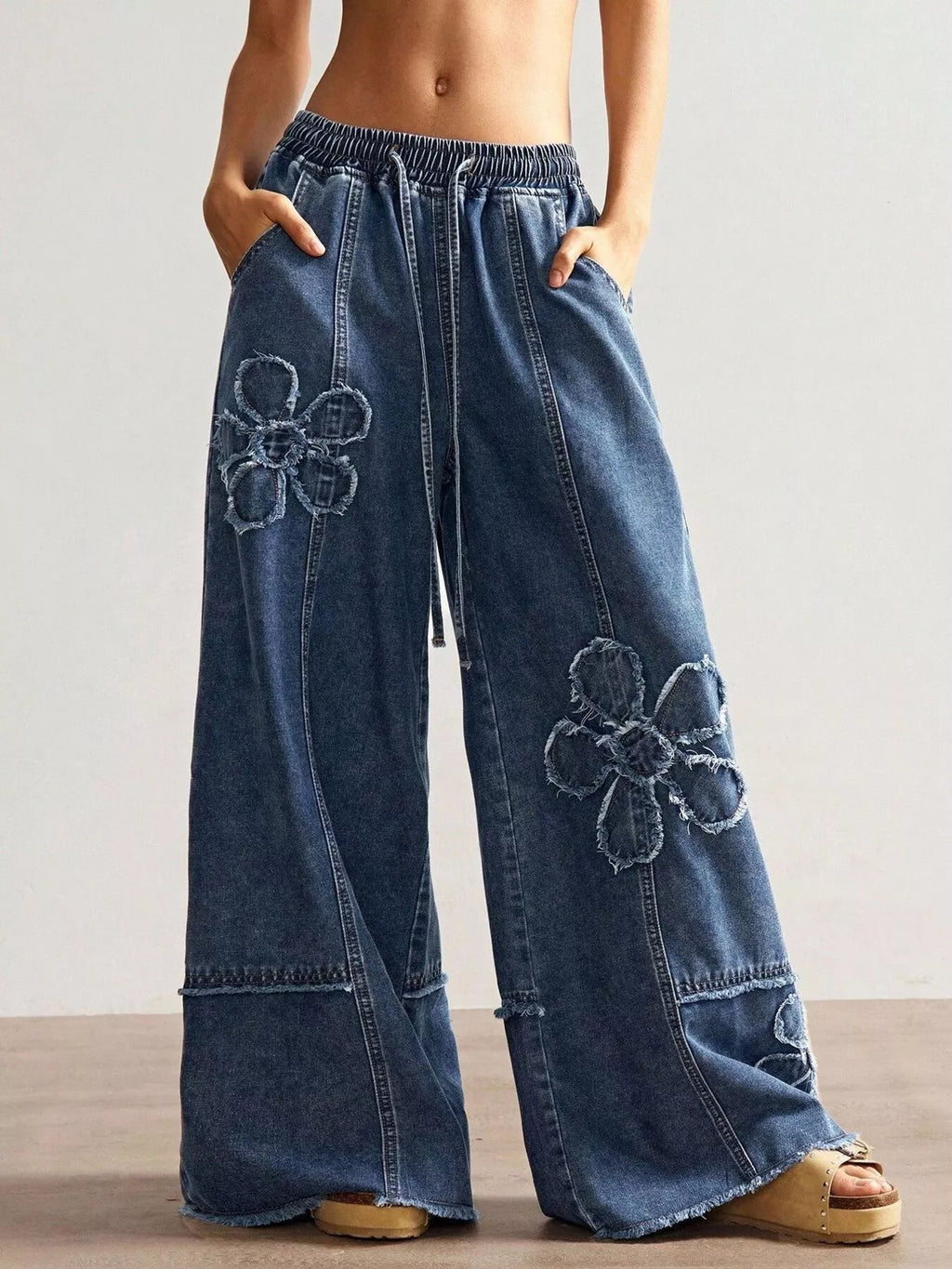 Wide leg jeans with floral appliques from Shopimist, showcasing detailed floral embroidery on light denim fabric.