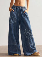 Wide leg jeans with floral appliques from Shopimist, showcasing detailed floral embroidery on light denim fabric.