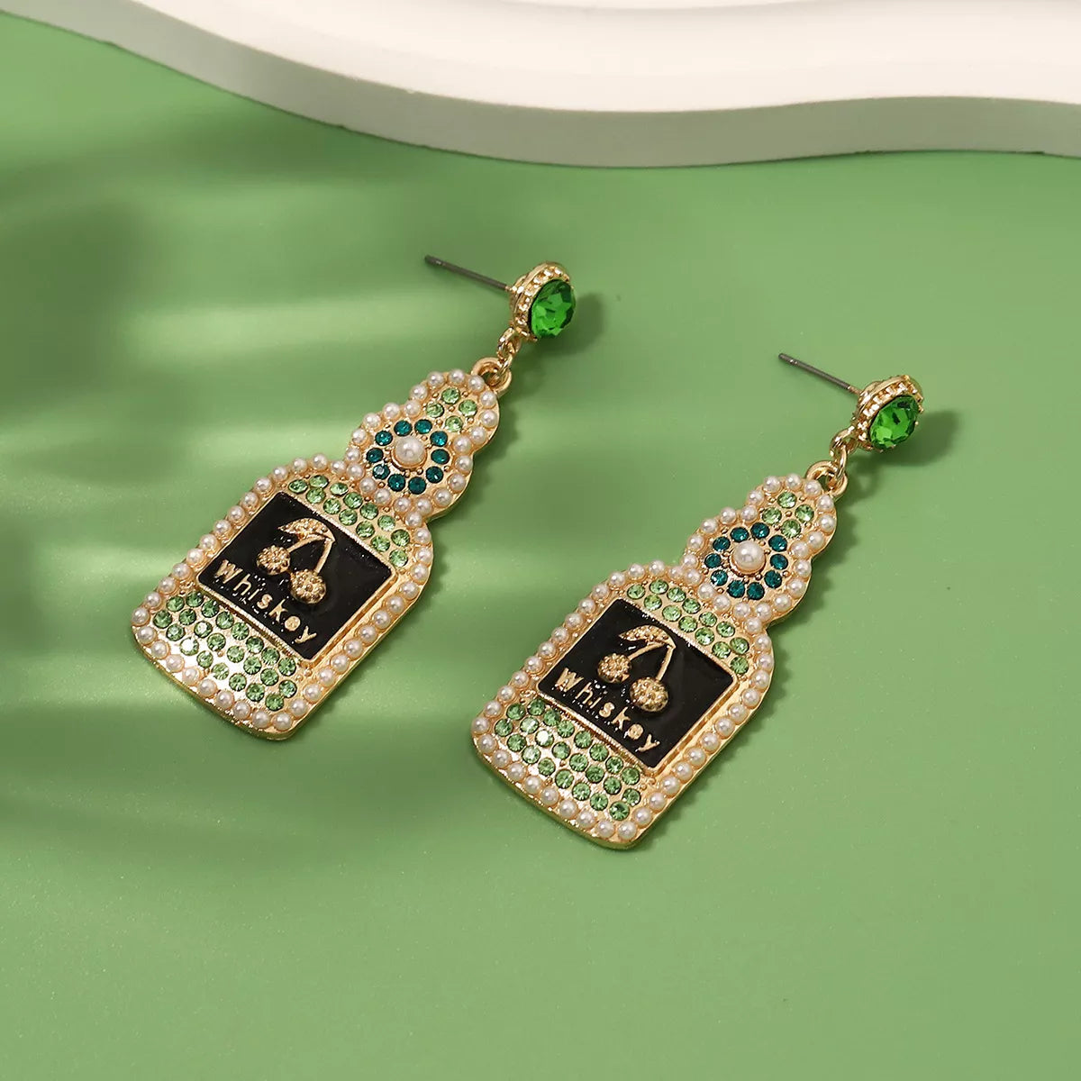 Whiskey bottle dangle earrings by Plush Fashion Hub featuring gold-tone whiskey bottle charms hanging from hooks.