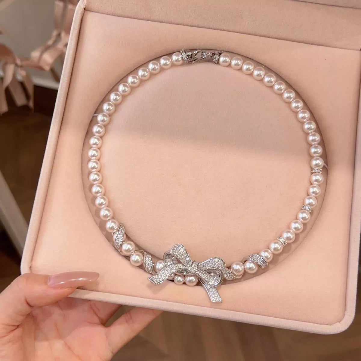 Elegant pearl necklace from Plush Fashion Hub featuring a delicate bow pendant, perfect for stylish accessories.