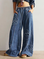 Wide leg jeans with floral appliques from Shopimist, featuring a relaxed fit and decorative floral embroidery on denim.