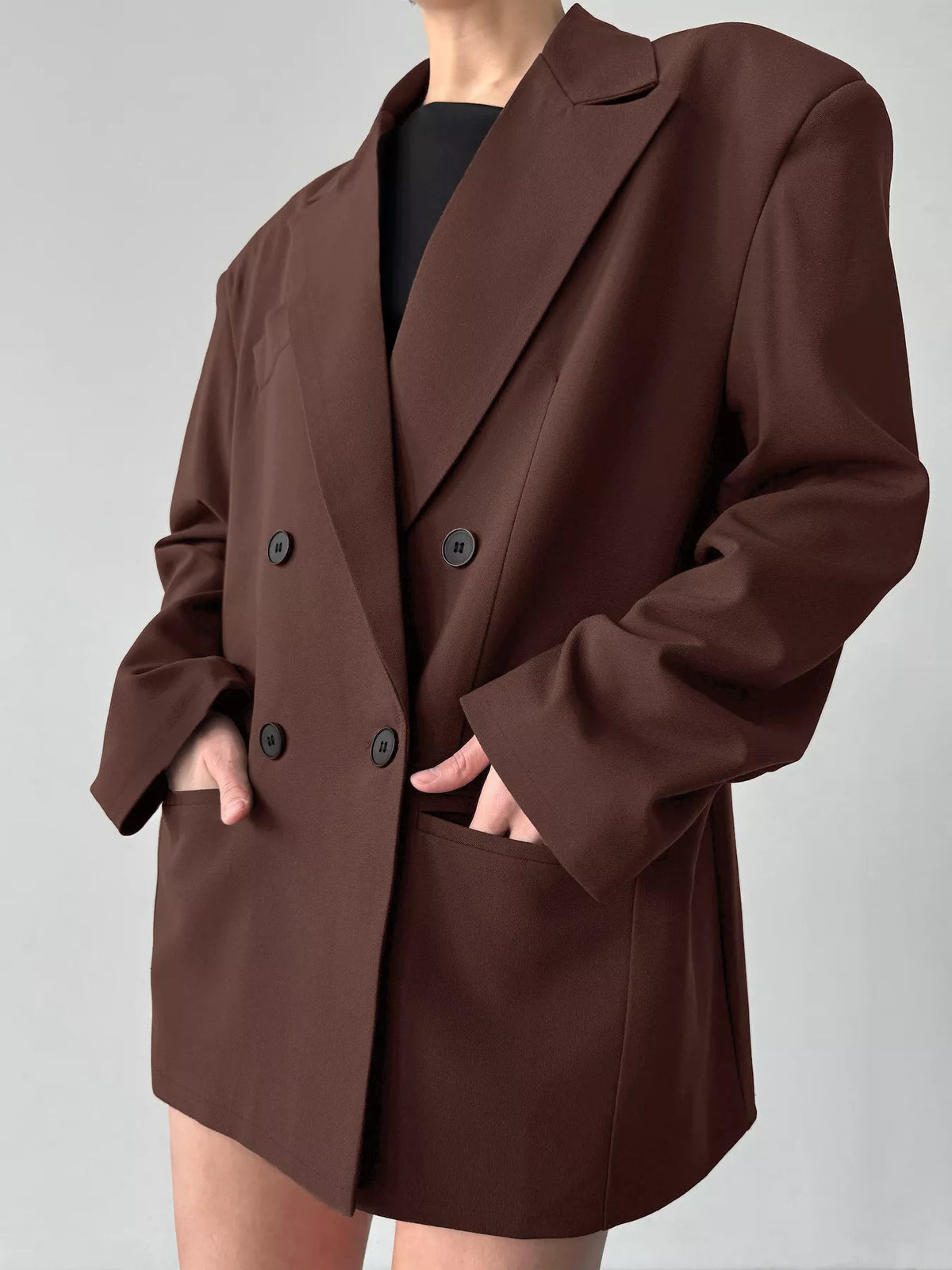 Black double-breasted blazer with lapel collar and structured fit, styled on a mannequin for a professional, fashion-forward look.