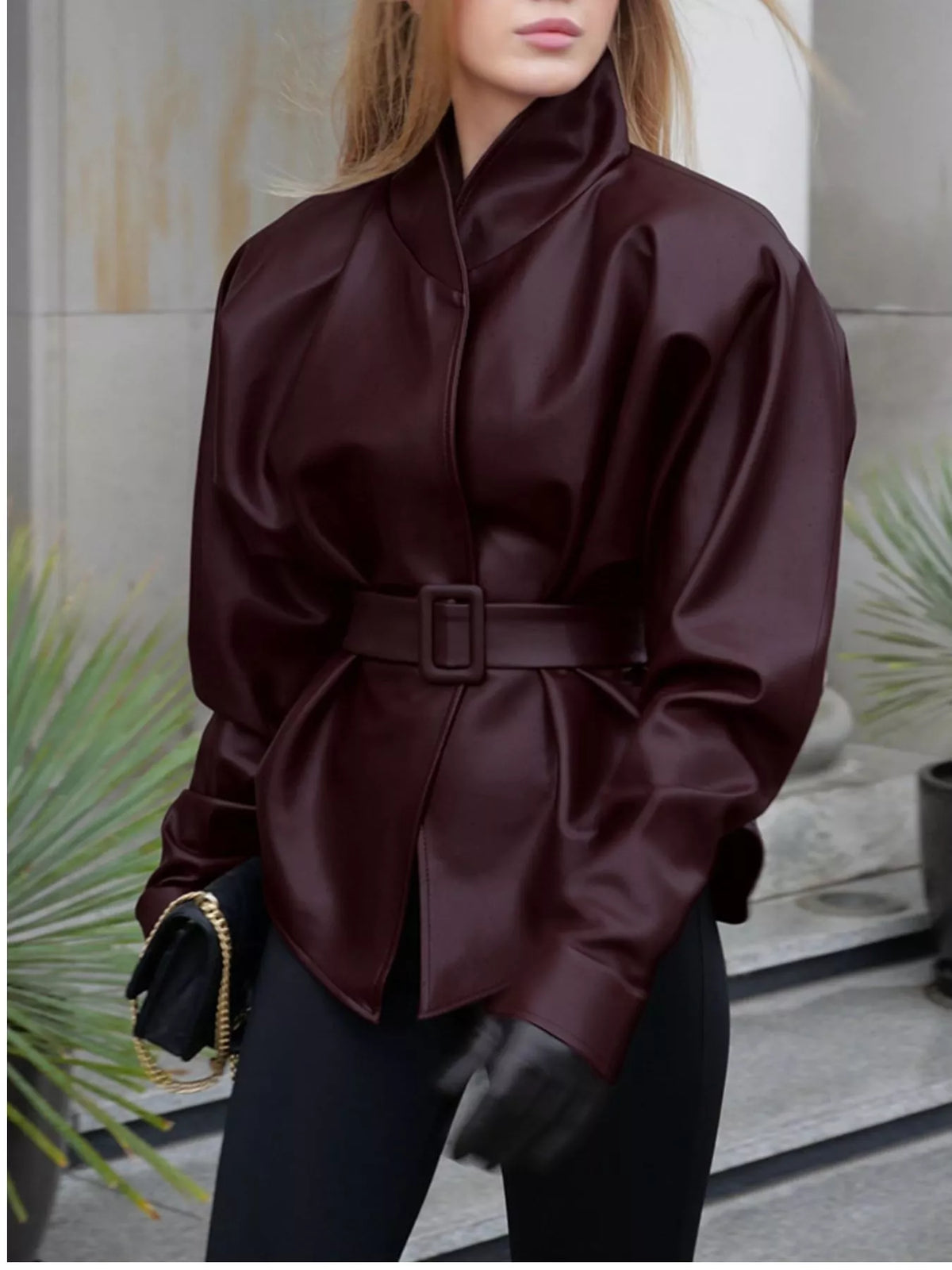 Women's faux leather jacket with stand collar and belt by Trendsi, showcasing a stylish, fitted design with smooth black leather appearance.