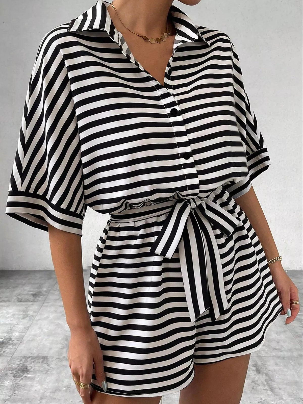 Striped button-up belted romper jumpsuit by Plush Fashion Hub, featuring a stylish design with a fitted waist and casual vibe.