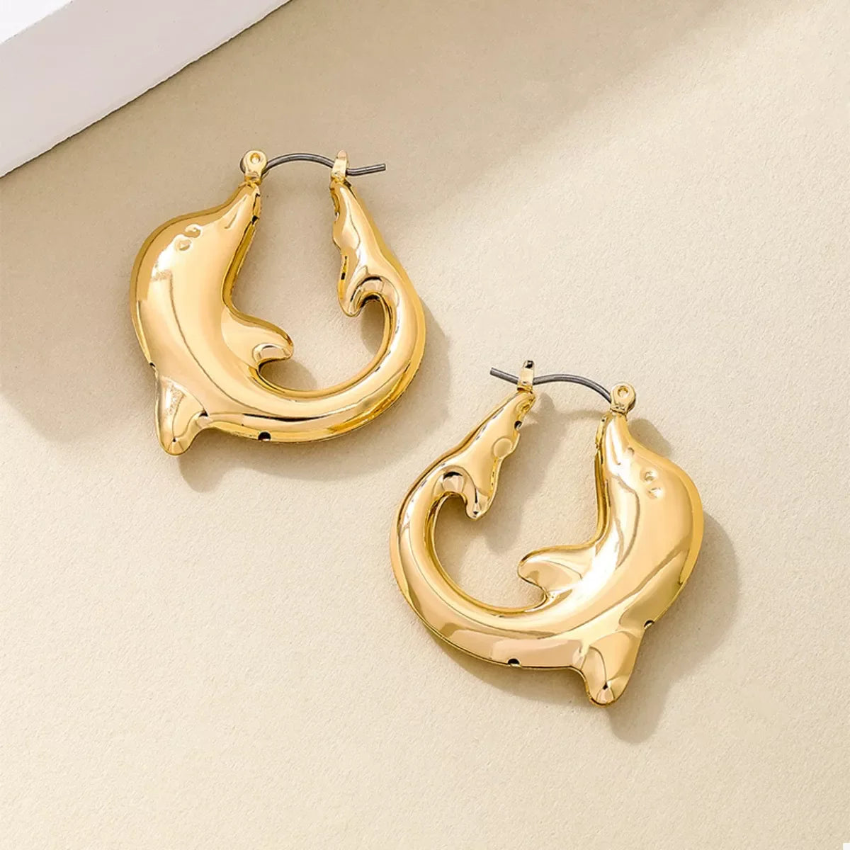 Gold-plated dolphin hoop earrings from Plush Fashion Hub, featuring shiny, detailed marine-inspired design for stylish wear.