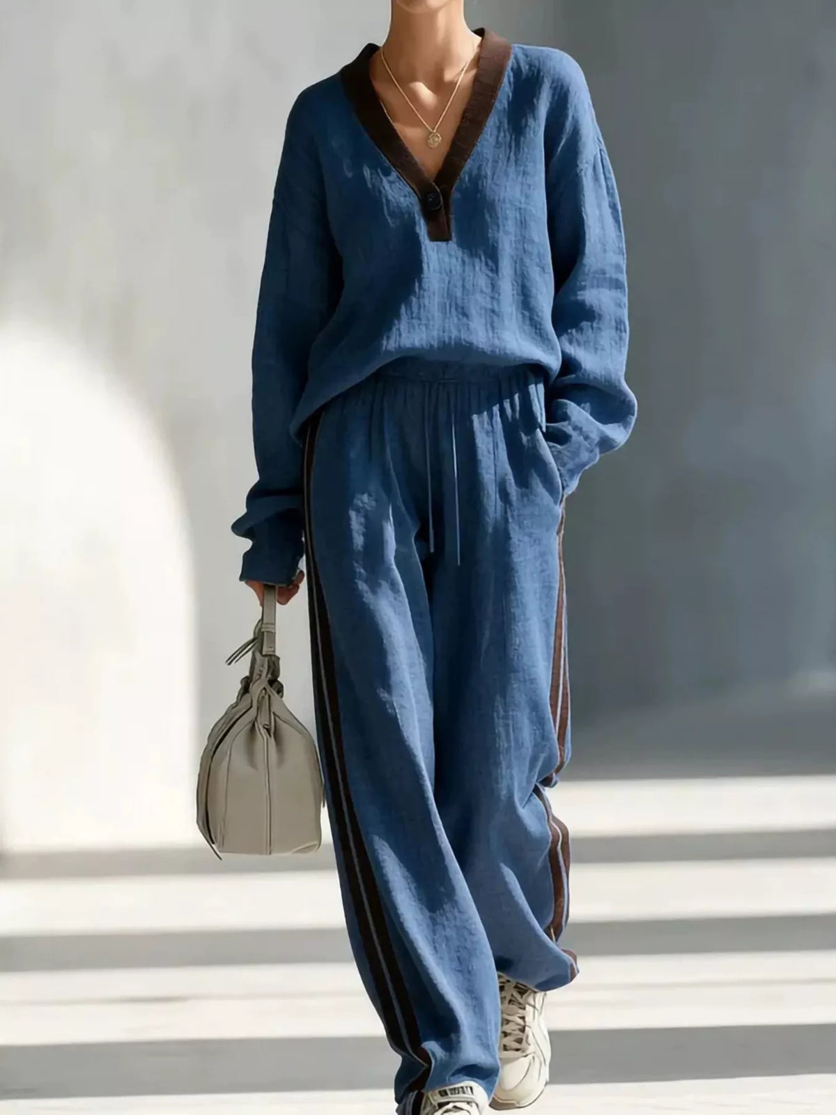 Women's contrast V-neck top and striped pants set by Trendsi, featuring a stylish V-neck top and matching striped pants.
