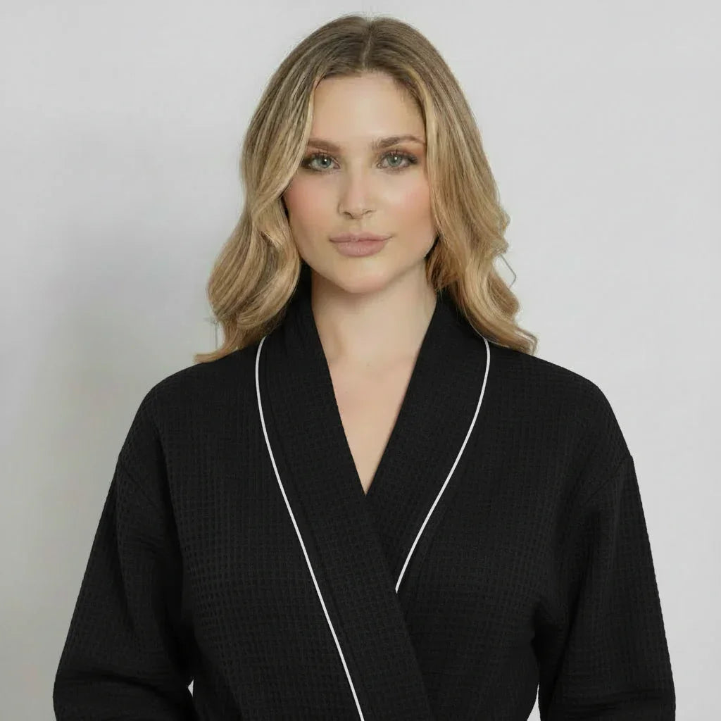 Front view of Lotus Linen women's knee-length black waffle robe with piping, showcasing its cozy, stylish design.