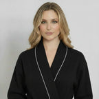 Front view of Lotus Linen women's knee-length black waffle robe with piping, showcasing its cozy, stylish design.