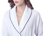 Front view of Lotus Linen women's knee-length waffle robe in white with piping, showing a cozy, lightweight bathrobe design.