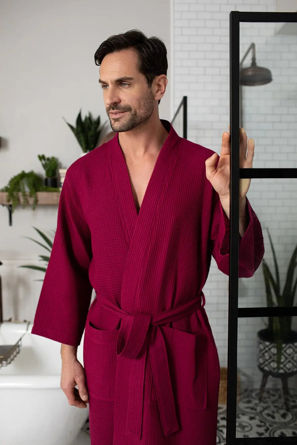 Red men's waffle spa bathrobe by Lotus Linen, lightweight and absorbent, shown hanging on a hook.