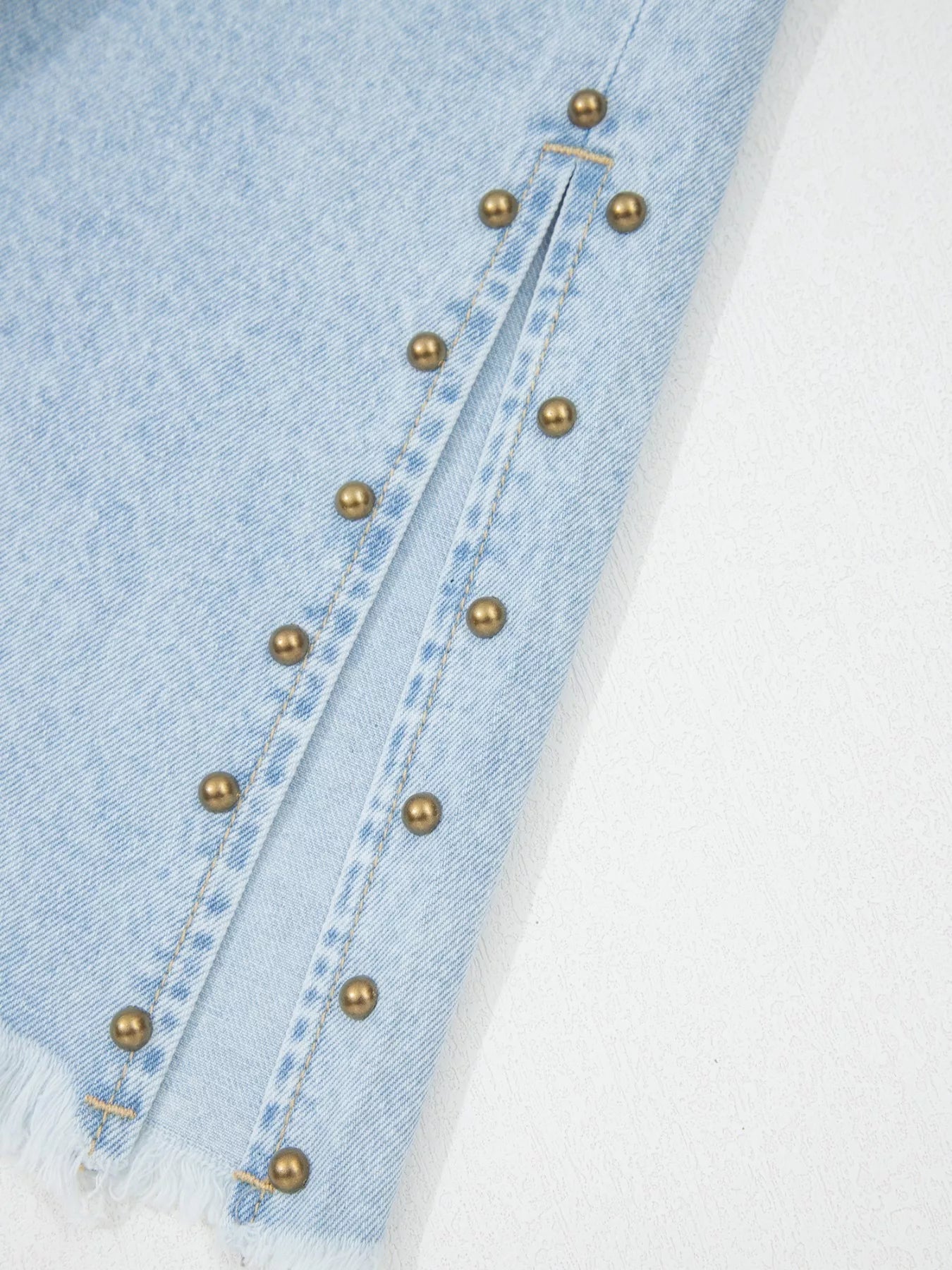 Trendsi studded wide-leg jeans with frayed hem and side slits, showcasing a trendy denim style with embellishments and distressed details.