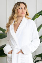 Women's ultra-soft plush bathrobe by Lotus Linen, white, cozy with a shawl collar and long sleeves, hanging on a hook.