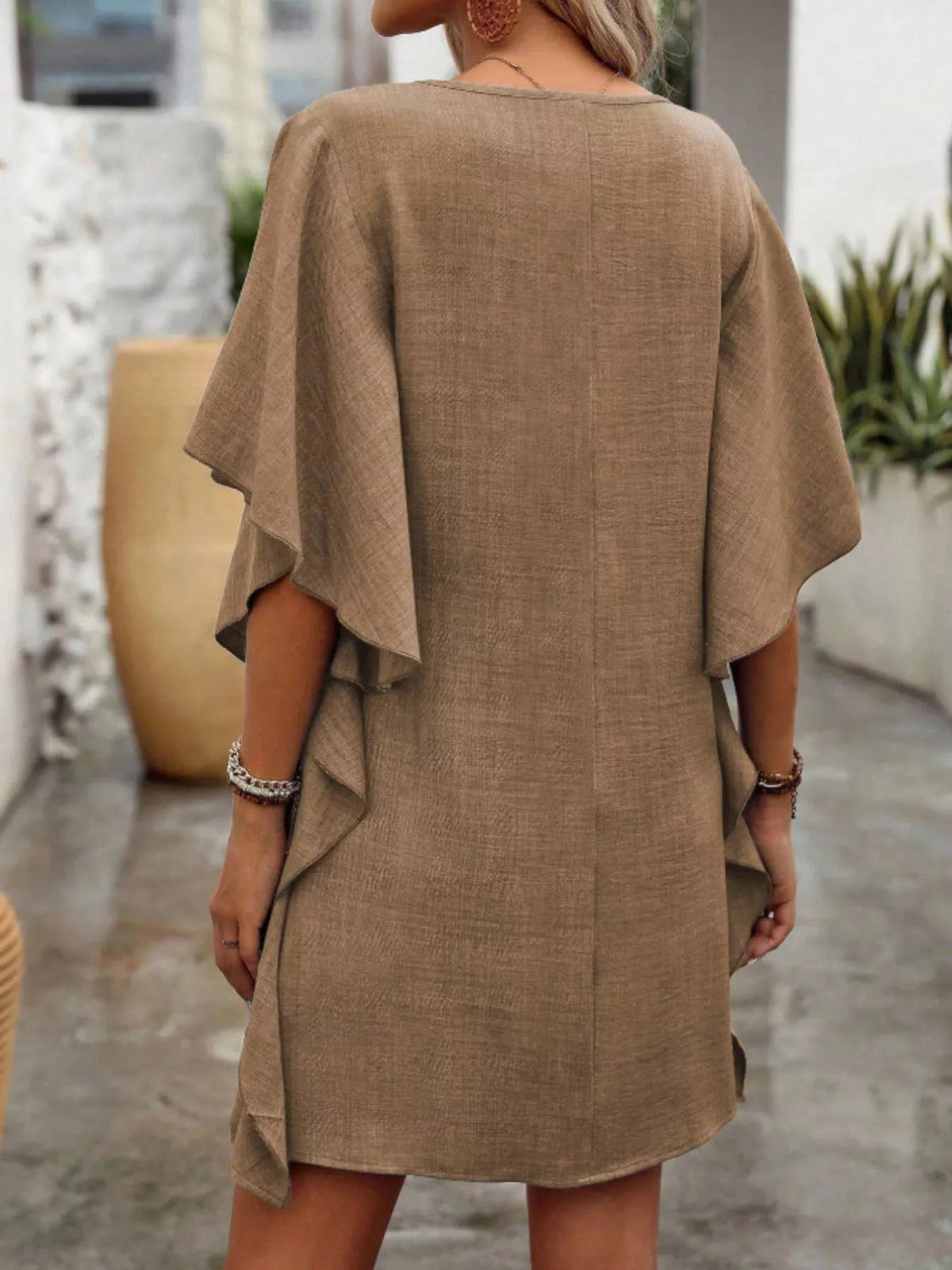 Women’s flowy V-neck casual mini dress with ruffled sleeves by Plush Fashion Hub, shown hanging on a hanger.