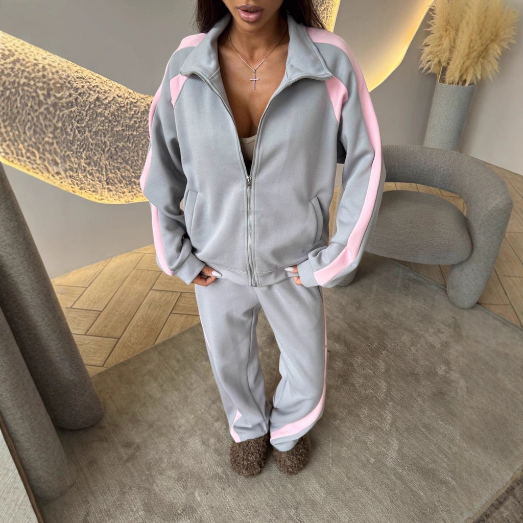 Women's long-sleeve zip-up jacket and sweatpants two-piece set by FitiqueFit, shown in a casual outdoor setting.