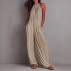 Women's sleeveless open-back wide-leg pleated jumpsuit by FitiqueFit, showing the stylish design and flowing fabric.