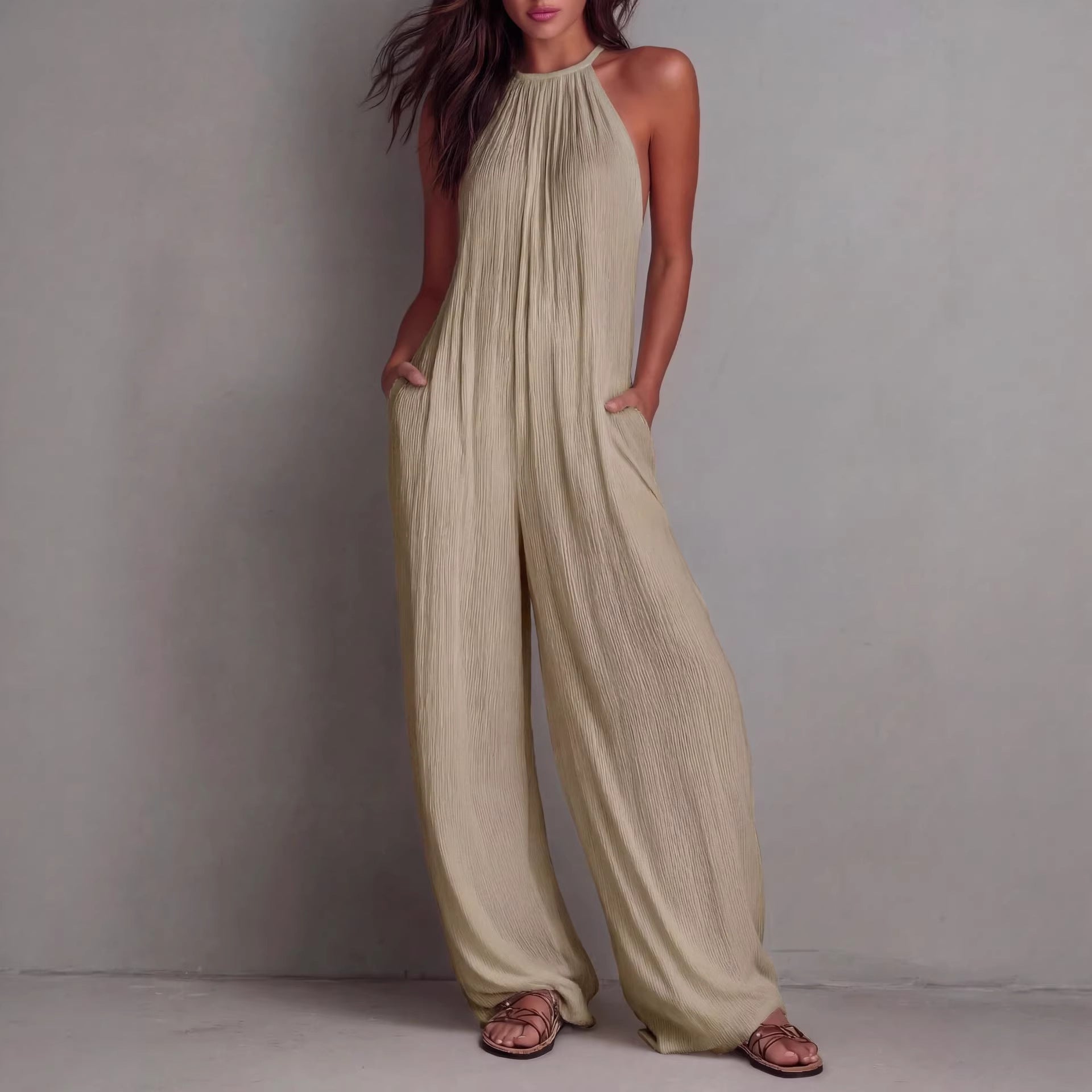 Women's sleeveless open-back wide-leg pleated jumpsuit by FitiqueFit, showing the stylish design and flowing fabric.