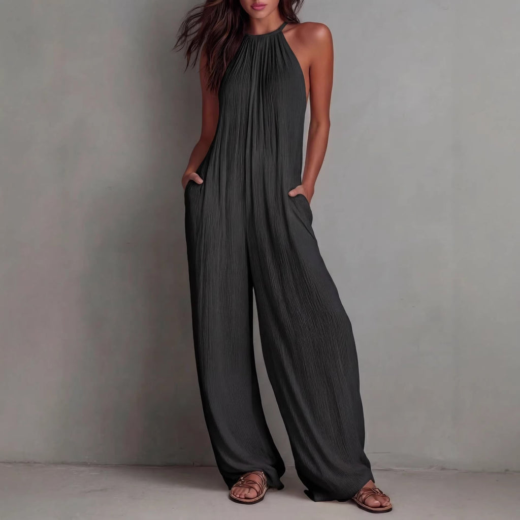 Women's sleeveless open-back wide-leg pleated jumpsuit by FitiqueFit, showing the relaxed fit and stylish design.